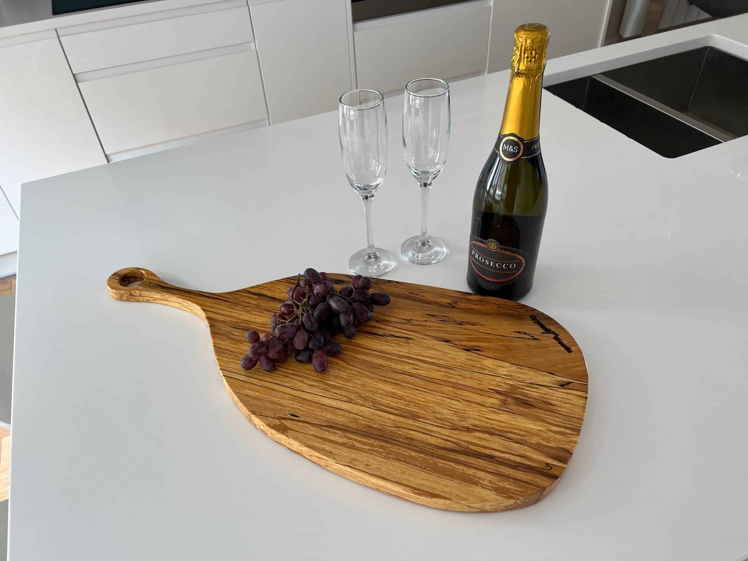 Spalted Beech Pizza and Sharing Platter 8 Paddle board pizza tray in Spalted Beech displaying a bottle of wine, grapes and two glasses