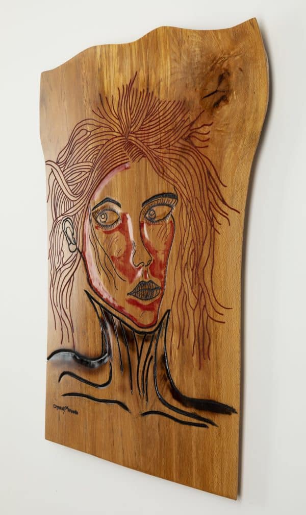 Angled side view of this Wooden wall art piece titled, Victim of Fashion carved and painted onto a piece of locally sourced English Beech, created by Crystal Woods