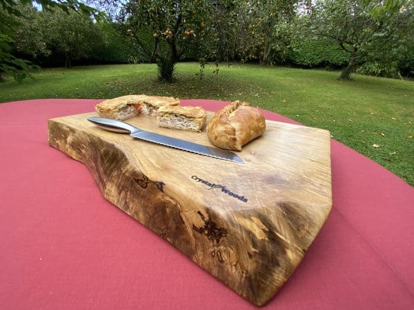 Close up view of this Live edge Sycamore chopping board, displaying homemade pastries, handcrafted by Crystal Woods from locally sourced wood in Devon, branded with their logo stamp