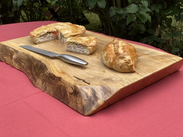 Live edge Sycamore chopping board, displaying a homemade pastries and knife, handcrafted by Crystal Woods, branded with their logo stamp