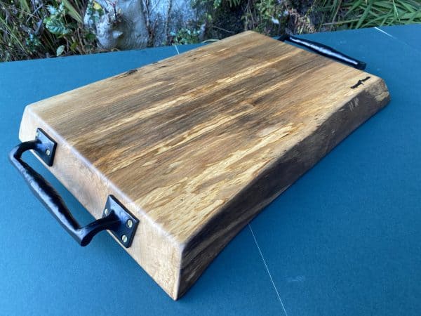 Angled close up shot of this sycamore chopping board with black metal handles, handcrafted by Crystal Woods, from locally sourced wood in Devon