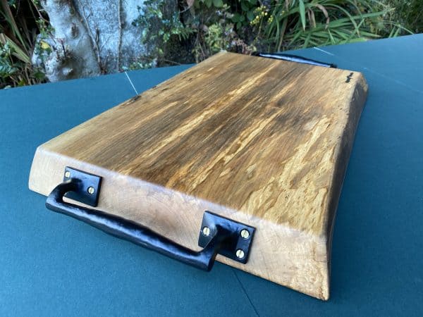 close up end view of this sycamore chopping board with black metal handles