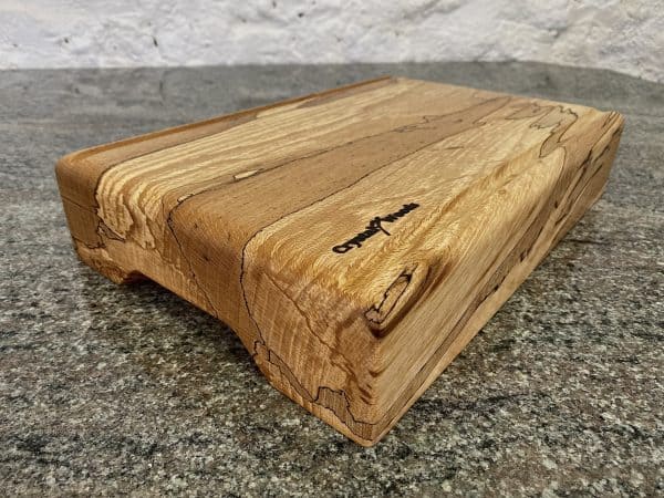 Front on angle view of this Extra Thick chopping board made from locally sourced English Spalted Beech, with two straight flute crumb grooves, created by Crystal Woods, finished in food safe oil, branded with their logo stamp