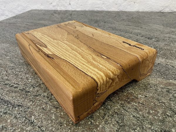 Angle view of this Extra Thick chopping board made from locally sourced English Spalted Beech, with two straight flute crumb grooves, created by Crystal Woods, finished in food safe oil, branded with their logo stamp