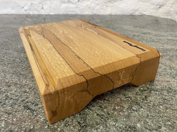 Close up angled view of this Spalted Beech V-Joint Crumb Groove Chunky Chopping Board – Extra Thick, hand crafted by Crystal Woods, finished in food safe oil, branded with their logo stamp, locally sourced wood from Devon