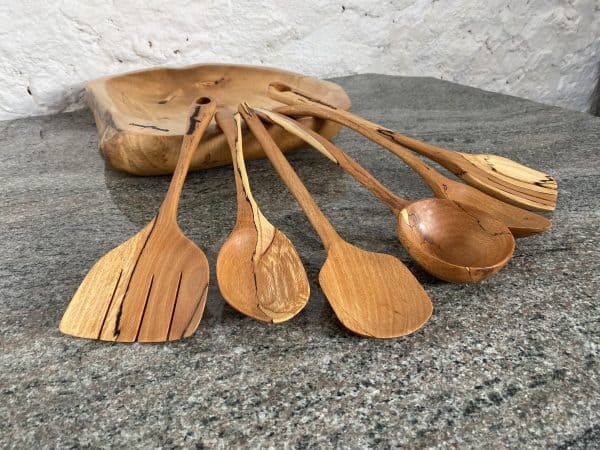 Close up of A Set of 6 Beech Serving spoons with a Ladle and two slotted serving spoons, from locally sourced wood in Devon, finished in food safe oil, handcrafted by Crystal Woods