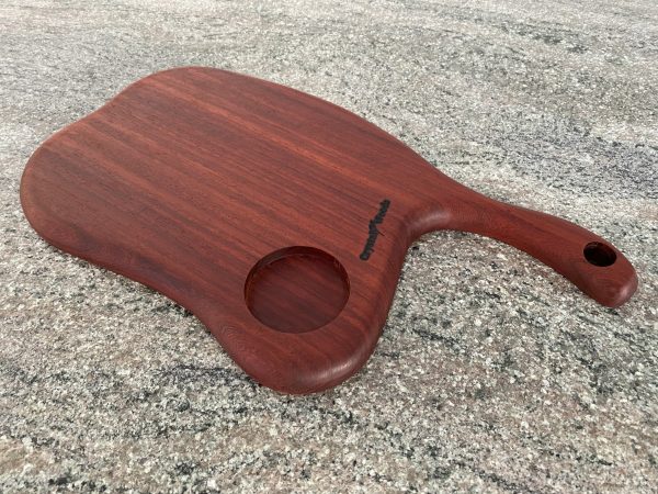 Close up view of this Slender Curved Meat Cleaver Style Charcuterie Board in Exotic Padauk Wood, with a scolloped indent to take a glass or wine bottle, handmade by Crystal Woods
