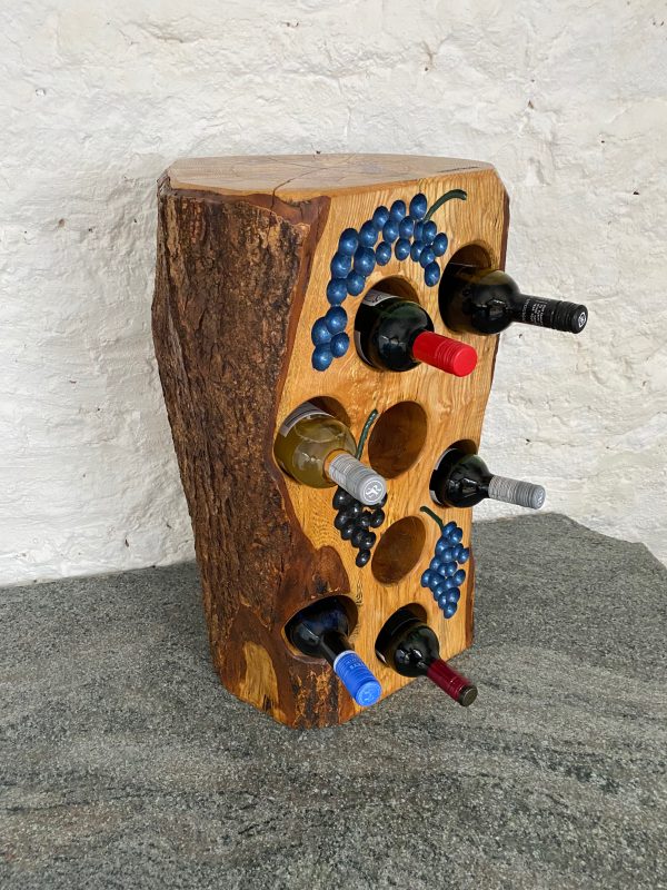 Angled side view of this small tree stump wine rack in English Ash that holds 8 bottles with bark still attached to the sides and back